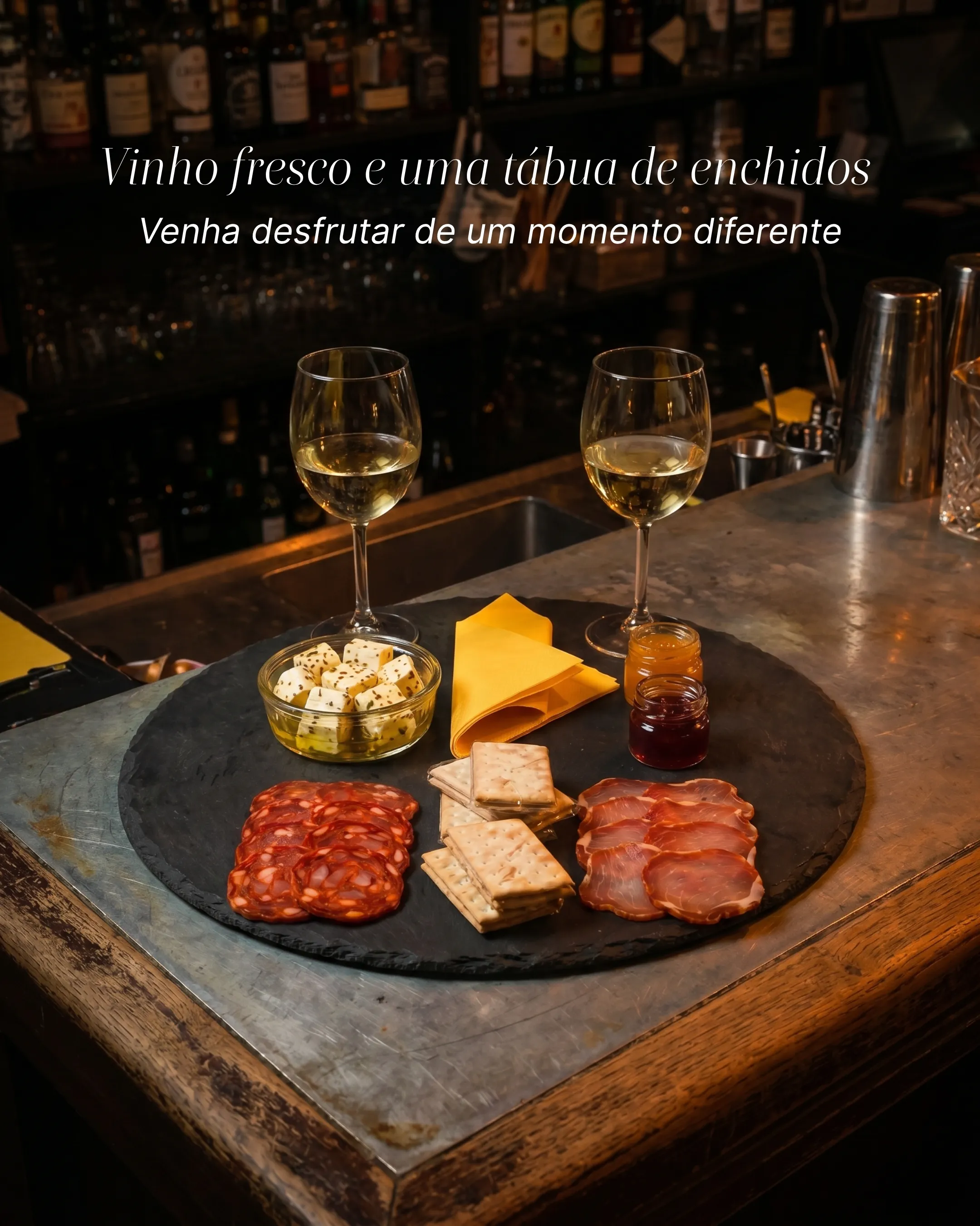 Tábua de queijos e enchidos com dois copos de vinho branco